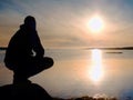 Man sit at evening sea. Hiker with backpack sit in squatting position along beach. Royalty Free Stock Photo