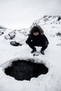 Man sit front on broken ice. Crack broke the thick ice. A frozen hole in the ice. Winter river. Frozen lake covered in snow. Huge