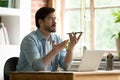 Man sit indoors holds cellphone talks to client on speakerphone Royalty Free Stock Photo