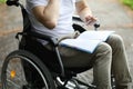 Man sit in wheelchair and take note in notebook in park. Royalty Free Stock Photo