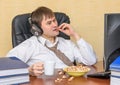 The man sits back in the office, eating popcorn and listening to music