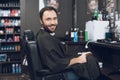 A man sits in a barber`s chair in a man`s barbershop, where he came to cut his hair. Royalty Free Stock Photo