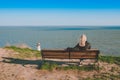 A man sits on a bench with his back and looks at the sea in the distance. A man looks at the sea Royalty Free Stock Photo