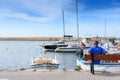 The man sits on a bench in the port and waits for the girl on a background of white yachts and boats