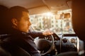 A man sits in a car cabin in and looks out at the street. Taxi driver in his car. Transportation concept. Royalty Free Stock Photo