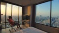 The man sits on an chair enjoys view of sunset of big city in his apartment on high floor of skyscraper.Man enjoying Royalty Free Stock Photo