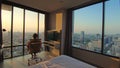 The man sits on an chair enjoys view of sunset of big city in his apartment on high floor of skyscraper. Man enjoys live Royalty Free Stock Photo