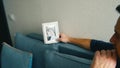 a man sits on the couch and looks pensively at his wedding photo and digests it face down