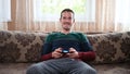 A man sits on the couch and plays the prefix at home Royalty Free Stock Photo