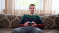 A man sits on the couch and plays the prefix at home Royalty Free Stock Photo