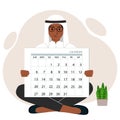 A man sits cross-legged and holds a large calendar glider in his hands. Concept of planning, make plans, schedule, event