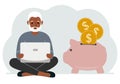 A man sits cross-legged with a laptop next to a pig piggy bank. Earning money, saving, saving money. Royalty Free Stock Photo