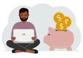 A man sits cross-legged with a laptop next to a pig piggy bank. Earning money, saving, saving money. Royalty Free Stock Photo