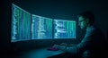 A man working on computer code in a dark room with multiple screens Royalty Free Stock Photo