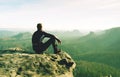 Man sits on edge of cliff against background of mist Royalty Free Stock Photo