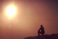 Man sits on edge of cliff against background of mist Royalty Free Stock Photo