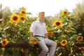 Man sits on fence near sunflowers Royalty Free Stock Photo