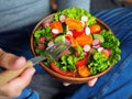 A man sits on the floor and eats a delicious green salad with orange tomatoes, radishes and cucumber