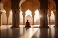 A man sits on the floor of a mosque and prays.