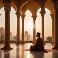 A man sits on the floor of a mosque and prays.