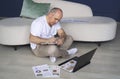 A man sits on the floor, works on laptops, studies reporting documents.