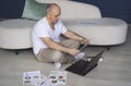 A man sits on the floor, works on laptops, studies reporting documents.