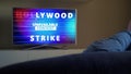 Man sits in front of TV and turns on news about Hollywood Strike 2023