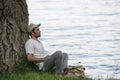 Young man is resting near a tree on the river Bank Royalty Free Stock Photo