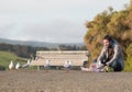 Man sits on the ground and feeds seagulls at sunset