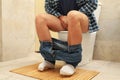 A man sits with his pants down on the toilet Royalty Free Stock Photo