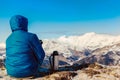 Man sits and looks at the snowy mountains