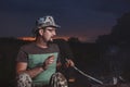 Man sits at night around the fire from which sparks fly, in the summer under the open sky Royalty Free Stock Photo