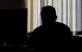 Man sits in the office at the computer. only silhouette. he looks at the cameras on the monitor