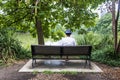 Man sits on park bench staring out at lake