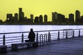 Man sits on park bench watching the sunset over Hudson River in New York City Royalty Free Stock Photo