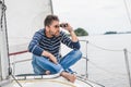 Man sits on sailing yacht and looks through binoculars Royalty Free Stock Photo