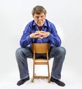 Man sits on a small wooden chair Royalty Free Stock Photo