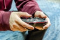 man sits on sofa holding game controller, playing remote controlled videogame. Gamepad in hands Royalty Free Stock Photo
