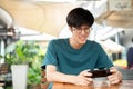 A man sits at a table outdoors, looking at his smartphone, playing a mobile game or watching a video Royalty Free Stock Photo
