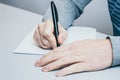 Man sits at the table and writes with a pen on paper Royalty Free Stock Photo