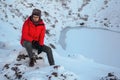 A man sits on top of the crater lake Kerid. Winter travel in Iceland. Portre men in a red jacket against the backdrop of a volcano