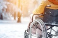 A man sits on a wheelchair, breathes fresh air, walking through a snowy park. People with special needs Royalty Free Stock Photo