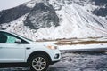 A man sits in a white car on the background of mountains in Iceland. Iceland transport in winter. Euro-trip Royalty Free Stock Photo