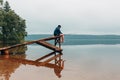 Man sits on a wooden bridge waits when the fish are biting. Royalty Free Stock Photo