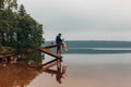 Man sits on a wooden bridge waits when the fish are biting. Royalty Free Stock Photo