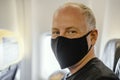 Man sitting in the airplane in protective face mask