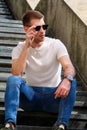 Man sitting alone on steps. Handsome boy with sunglasses. Male model posing for shooting, sitting on old stairs. Royalty Free Stock Photo