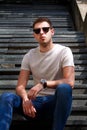 Man sitting alone on steps. Handsome boy with sunglasses. Male model posing for shooting, sitting on old stairs. Royalty Free Stock Photo