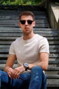 Man sitting alone on steps. Handsome boy with sunglasses. Male model posing for shooting, sitting on old stairs. Royalty Free Stock Photo