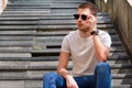 Man sitting alone on steps. Handsome boy with sunglasses. Male model posing for shooting, sitting on old stairs. Royalty Free Stock Photo